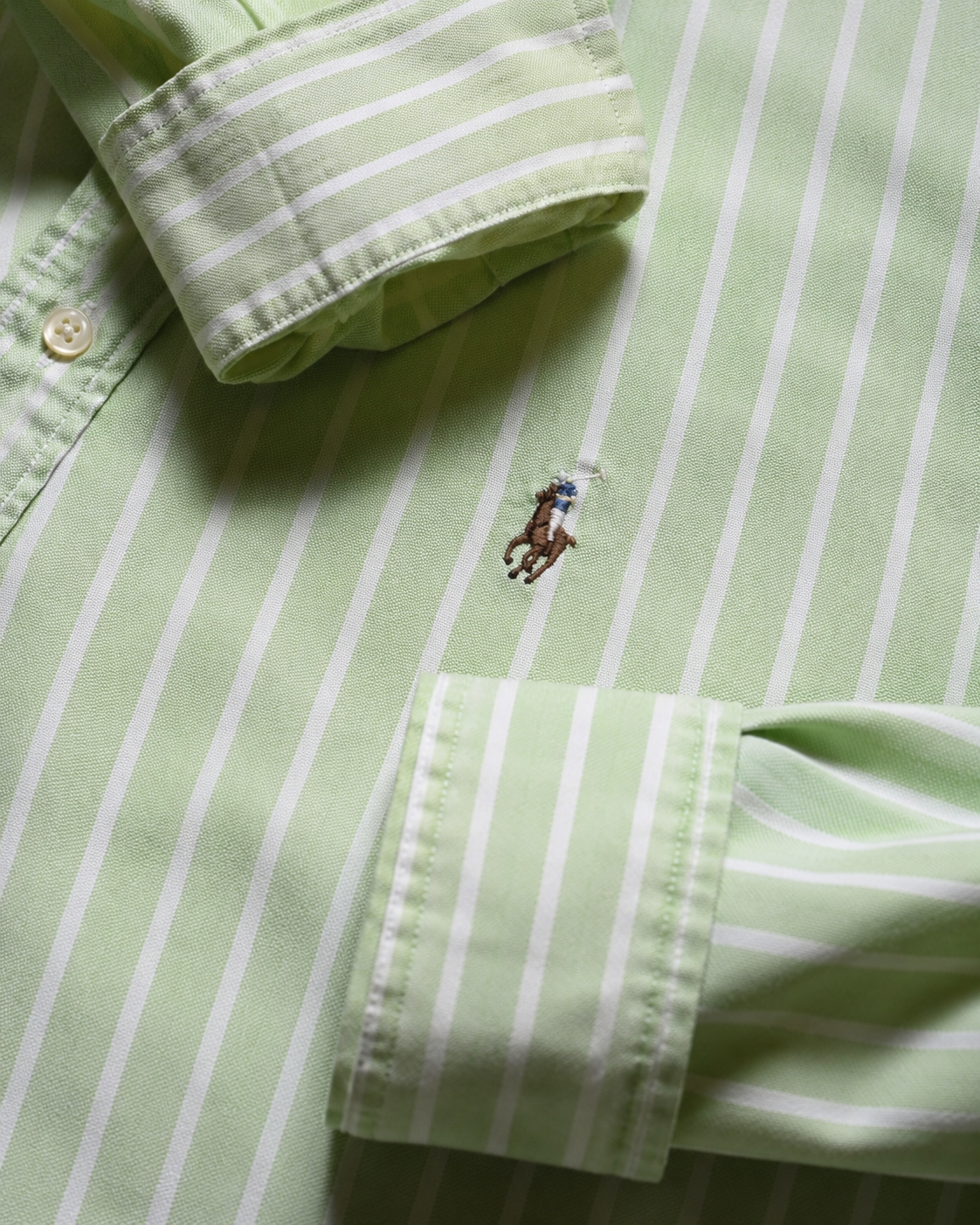 Close-up of a green and white striped vintage shirt with an Embroidered Ralph Lauren pony logo 