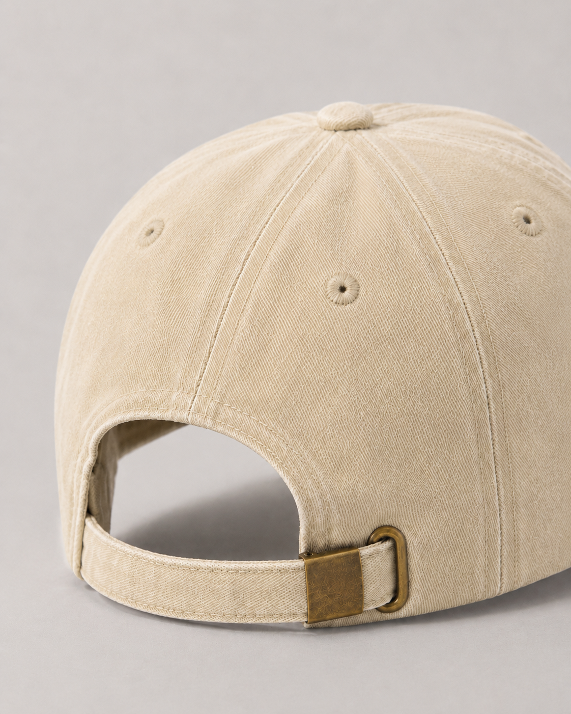Beige baseball cap with a brown leather strap on a gray background