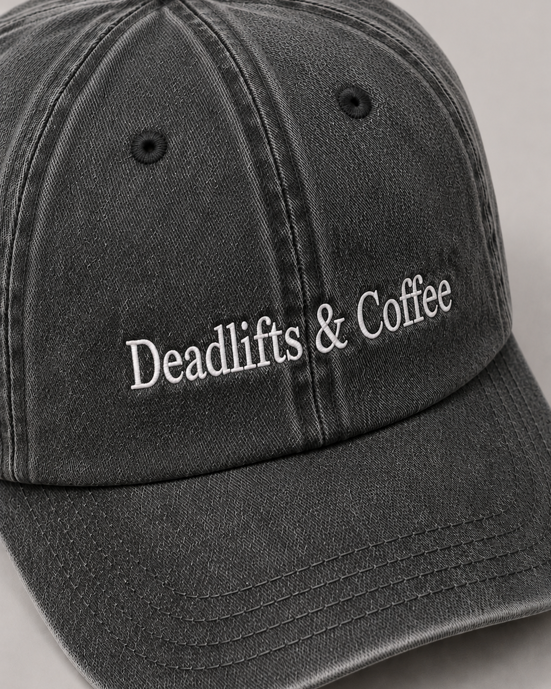 Black cap with 'Deadlifts & Coffee' text on a gray background