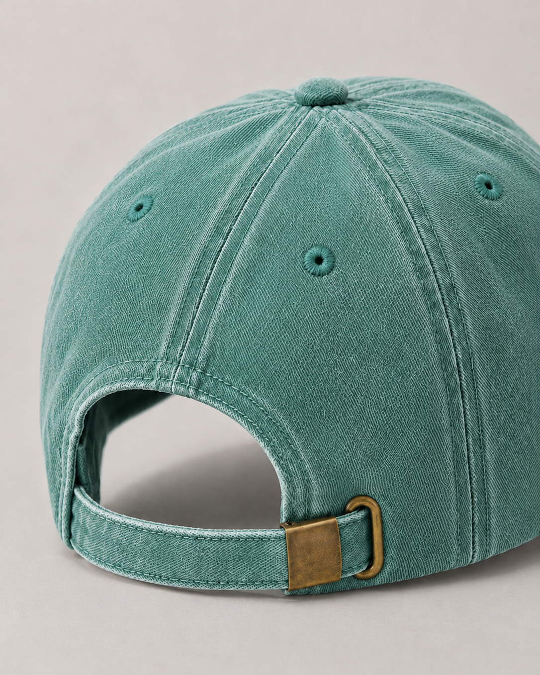 Teal baseball cap with a brown buckle on a light gray background
