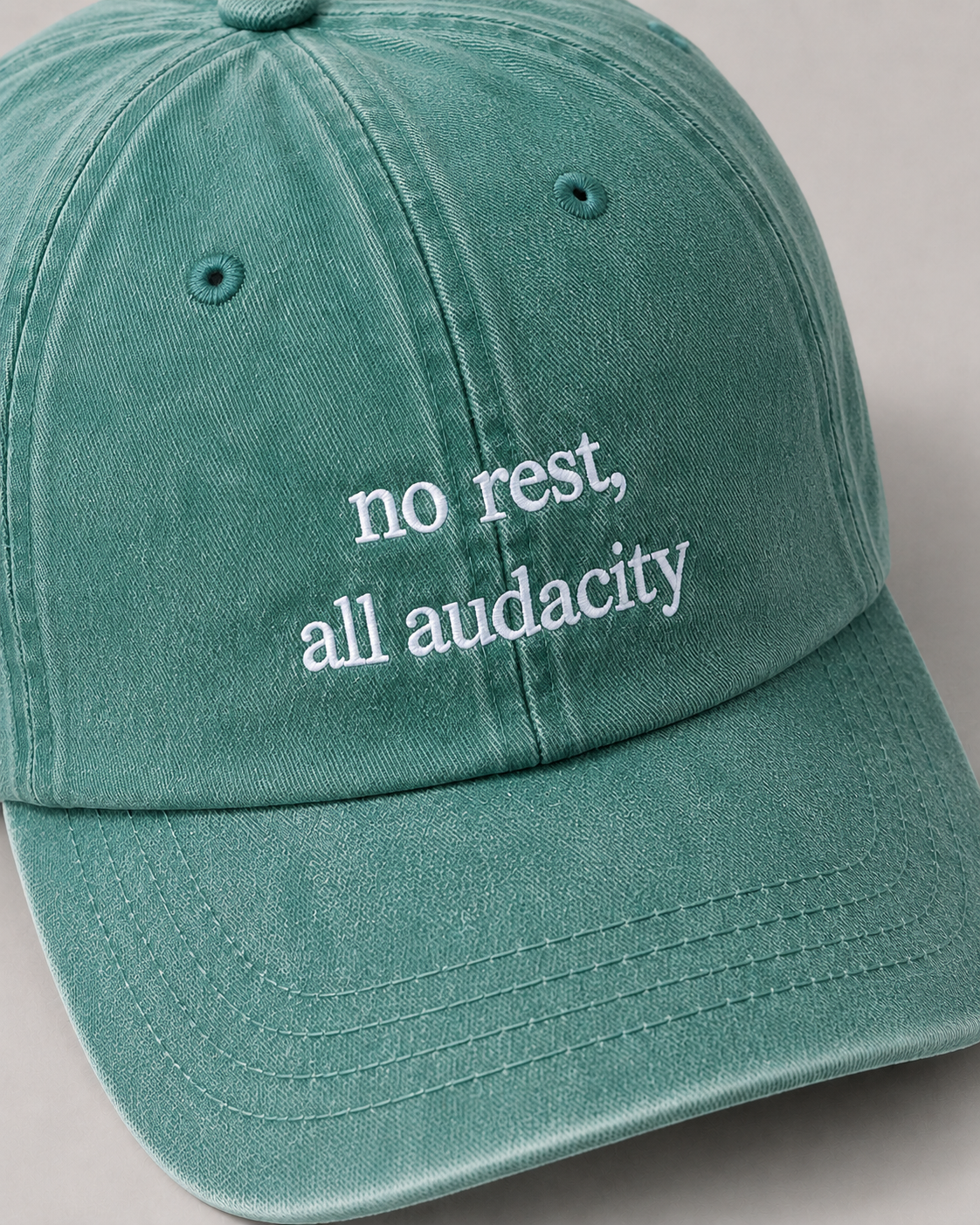 Green cap with 'no rest, all audacity' text on a gray background