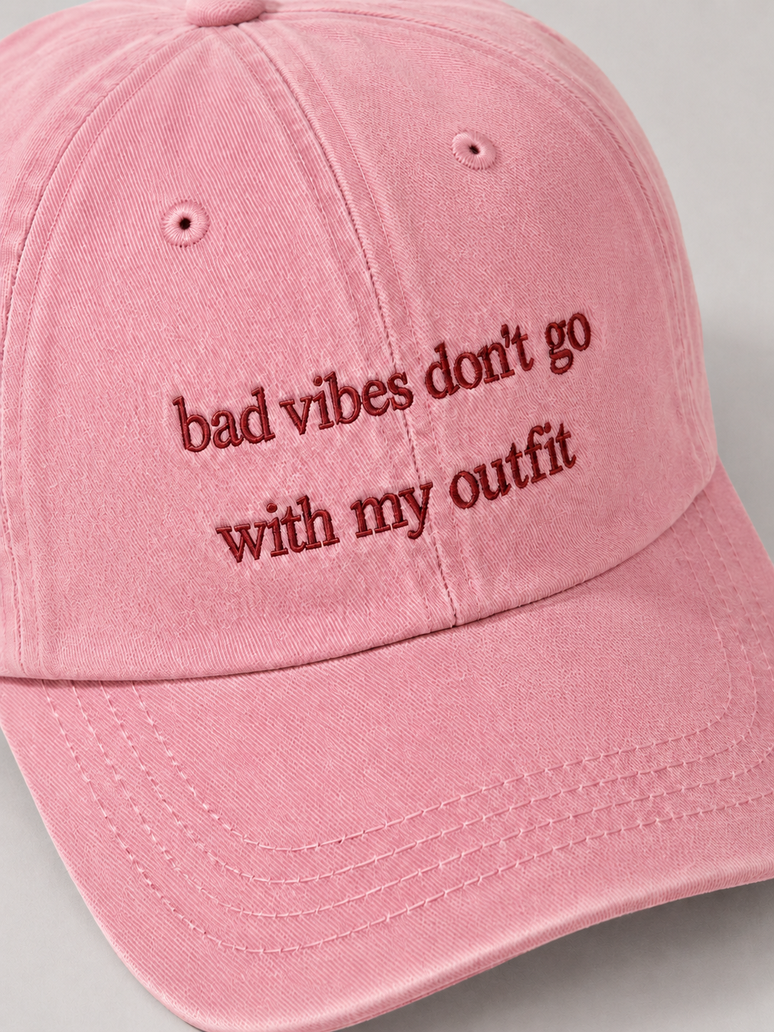 Pink cap with embroidered text on a gray background