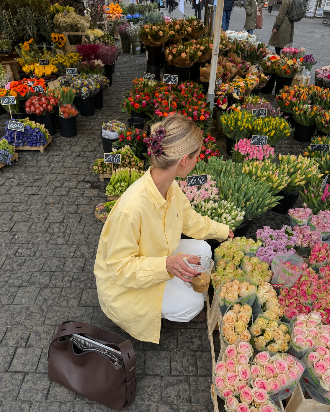 Woman in a yellow raincoat shopping at a flower market.